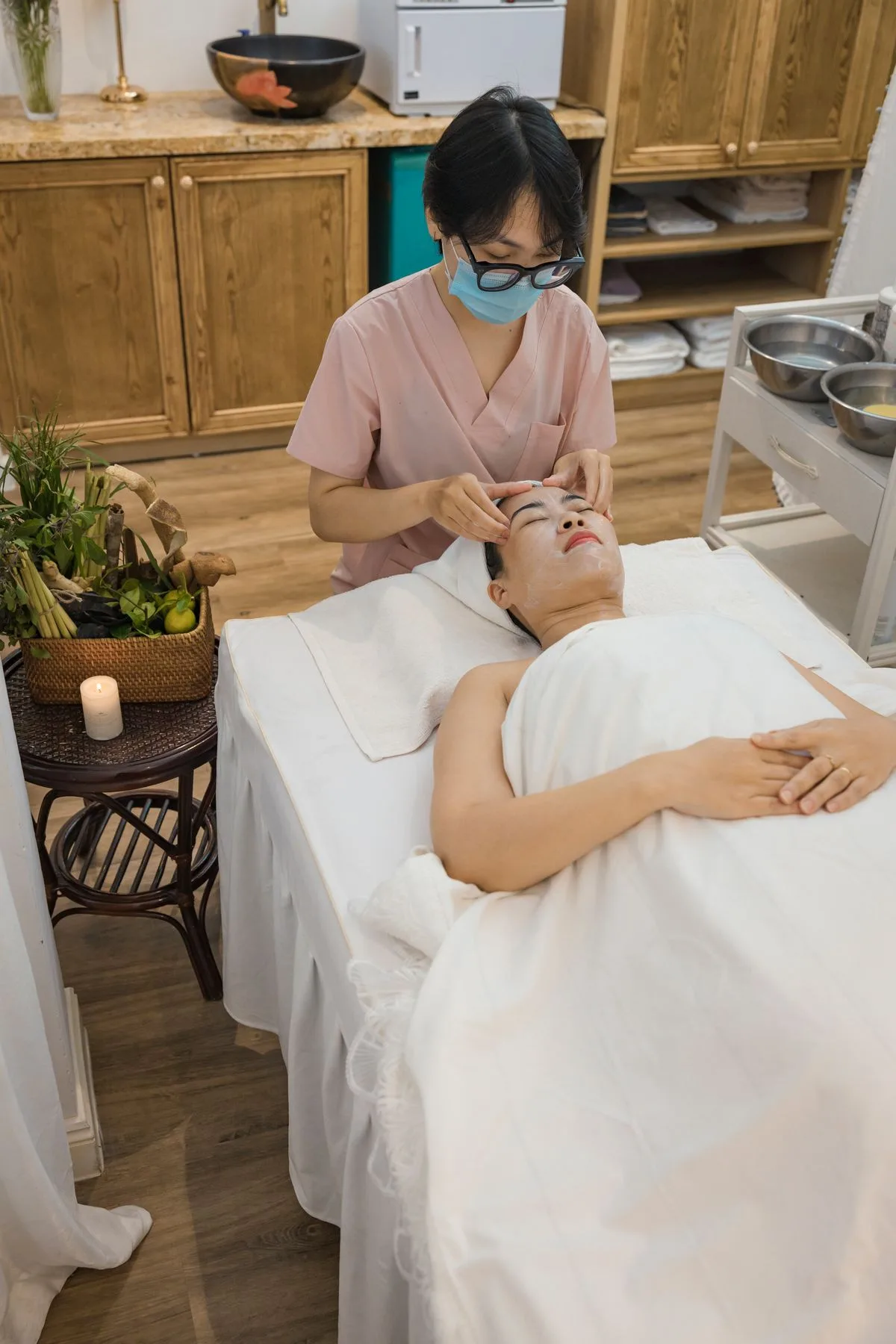Kỹ thuật viên đeo khẩu trang chăm sóc da cho khách
